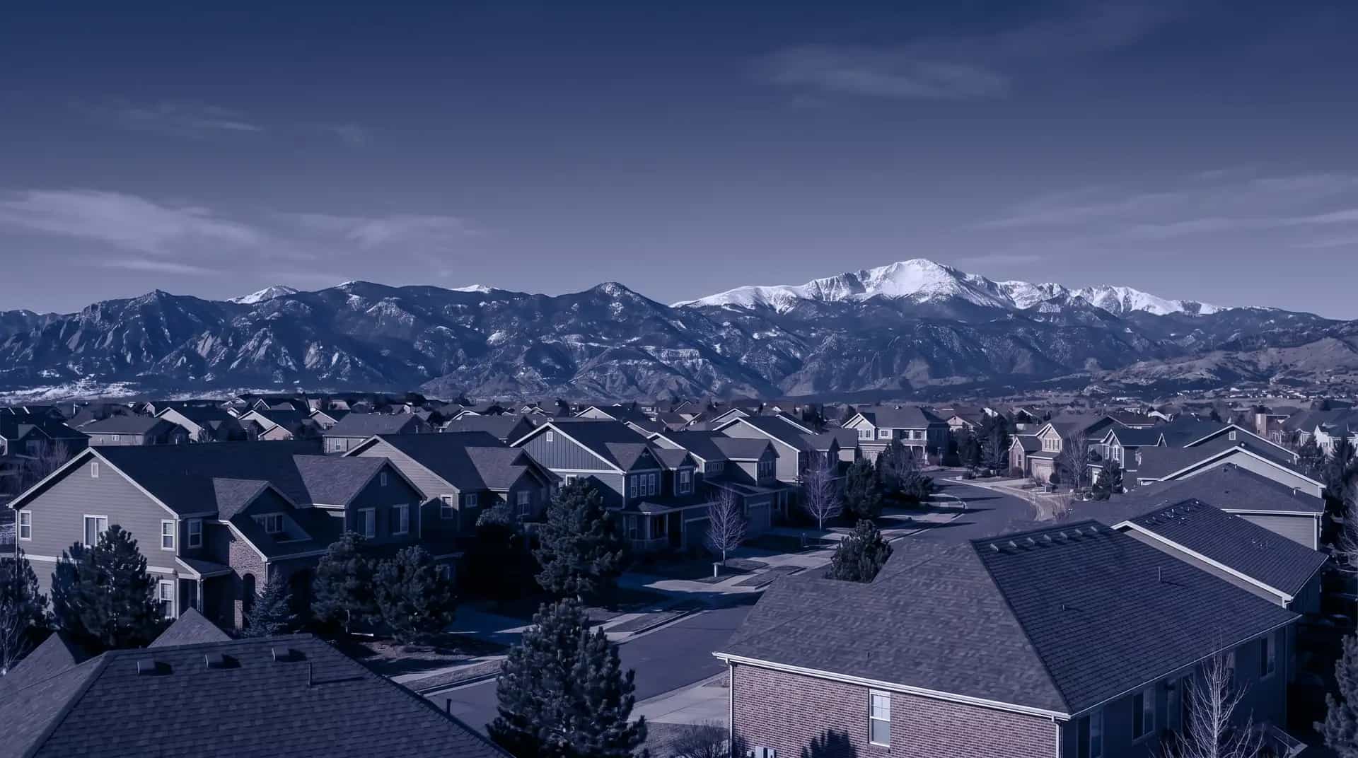 Colorado residential rooftops with the snow-capped Rocky Mountains in the distance