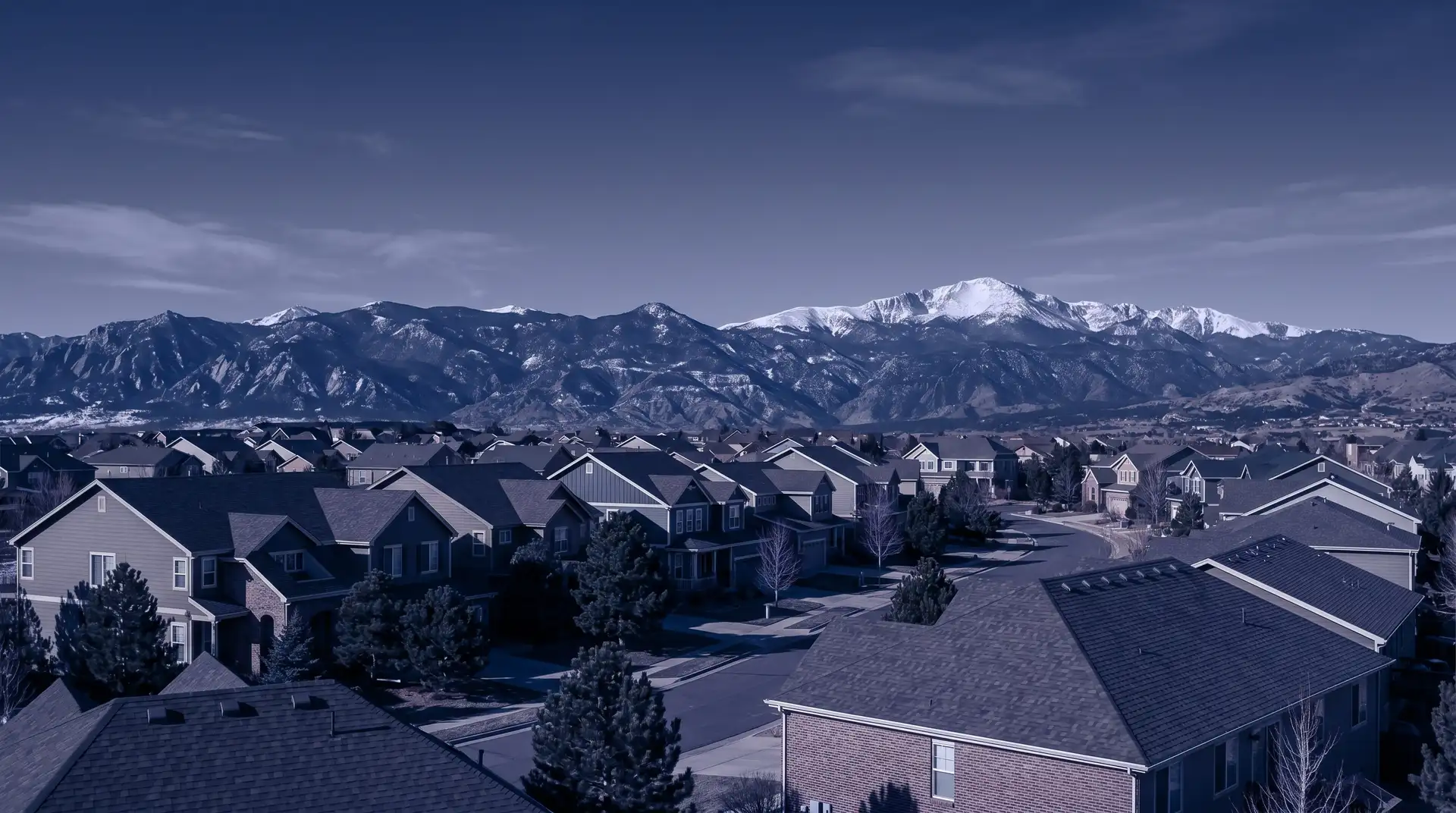Colorado residential rooftops with the snow-capped Rocky Mountains in the distance
