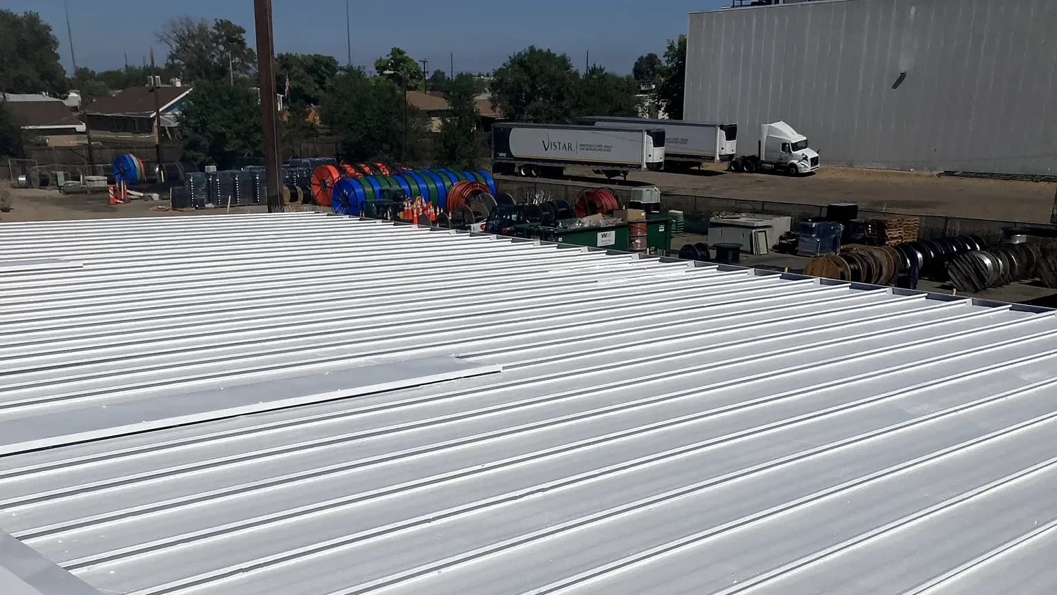 Finished bright white reflective coated metal roof on a commercial building in Denver, Colorado, with the Denver skyline in the background
