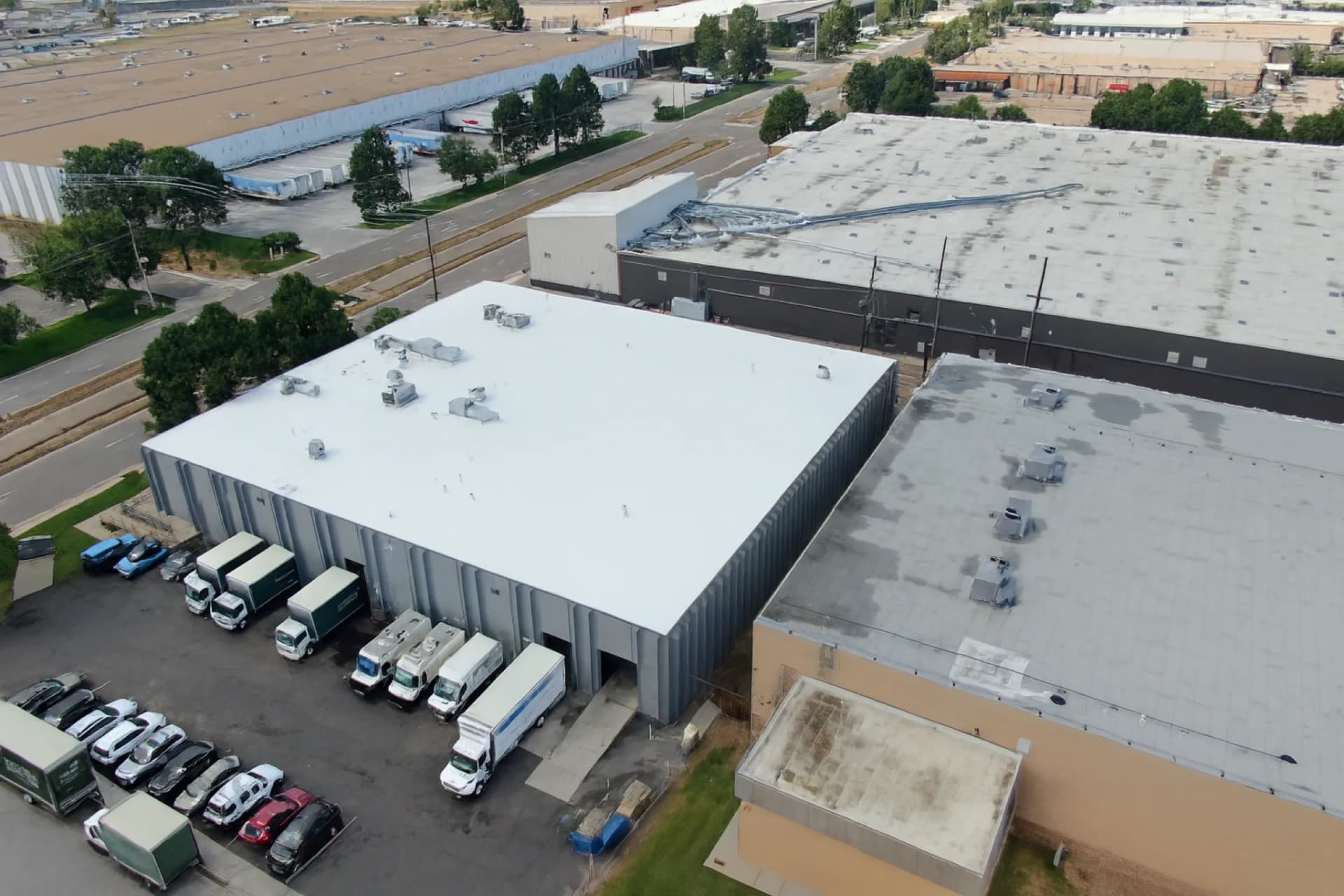 Aerial view of a completed white TPO membrane roof on the larger commercial warehouse building in the Northfield area of Denver, Colorado