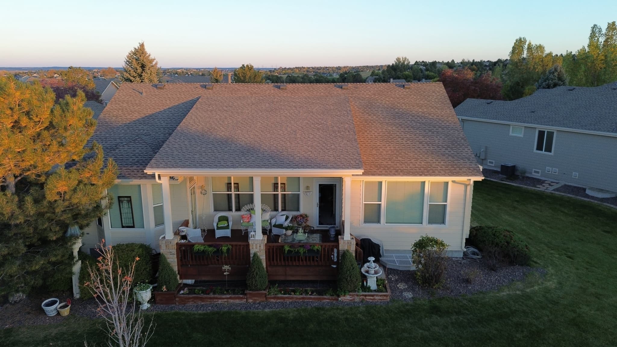 Aerial view of a Colorado home with a completed architectural asphalt shingle roof at golden hour, in a residential neighborhood near Castle Pines