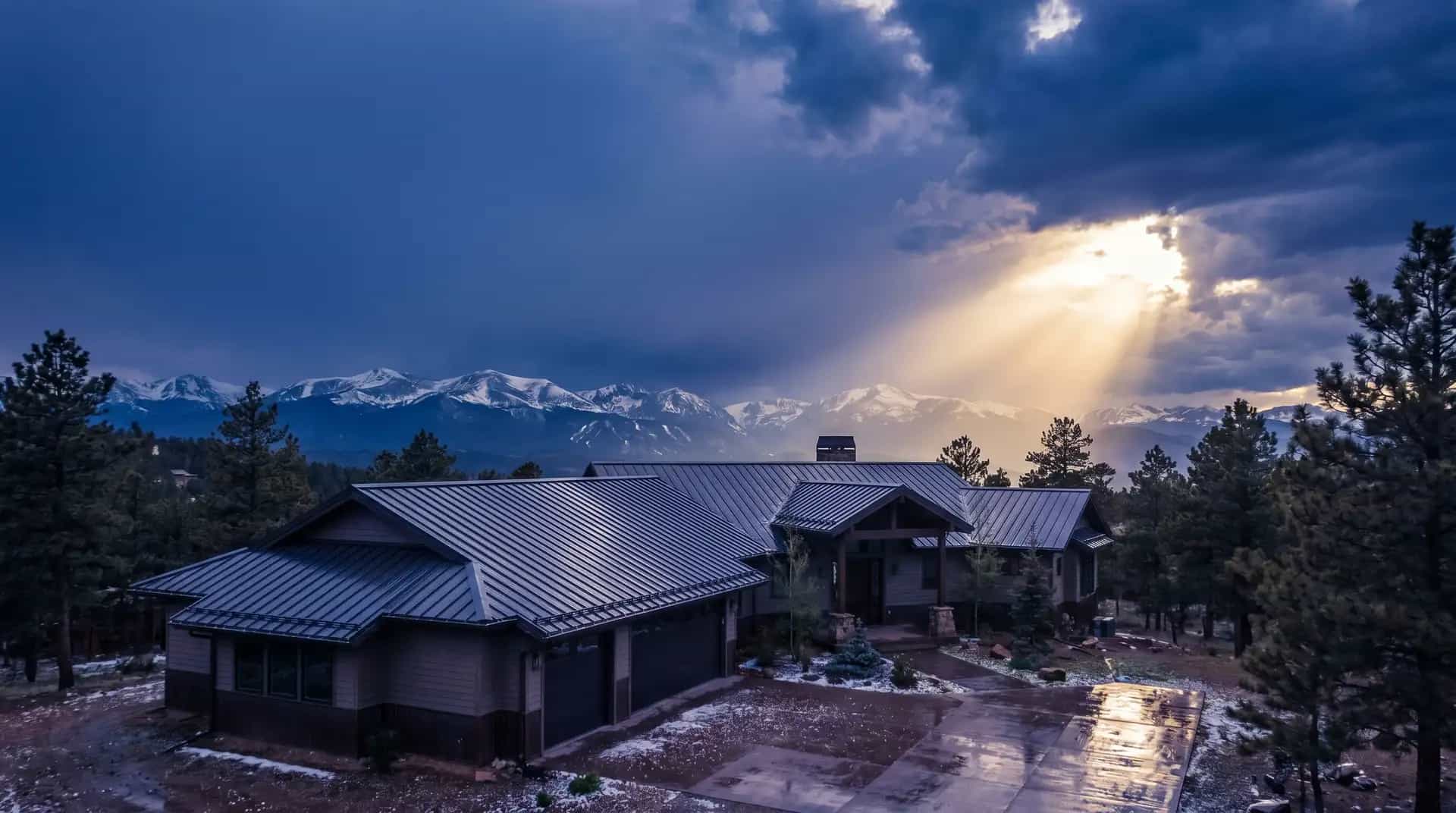A Colorado roof under a clearing storm sky with the Rocky Mountains in the distance