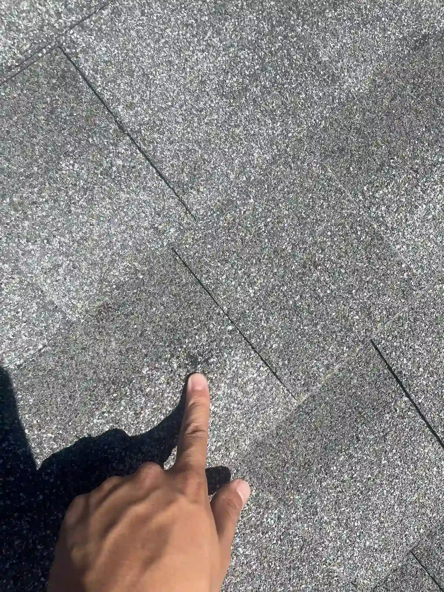 Roofer inspecting and documenting hail-damaged shingles on a residential roof in Aurora, Colorado