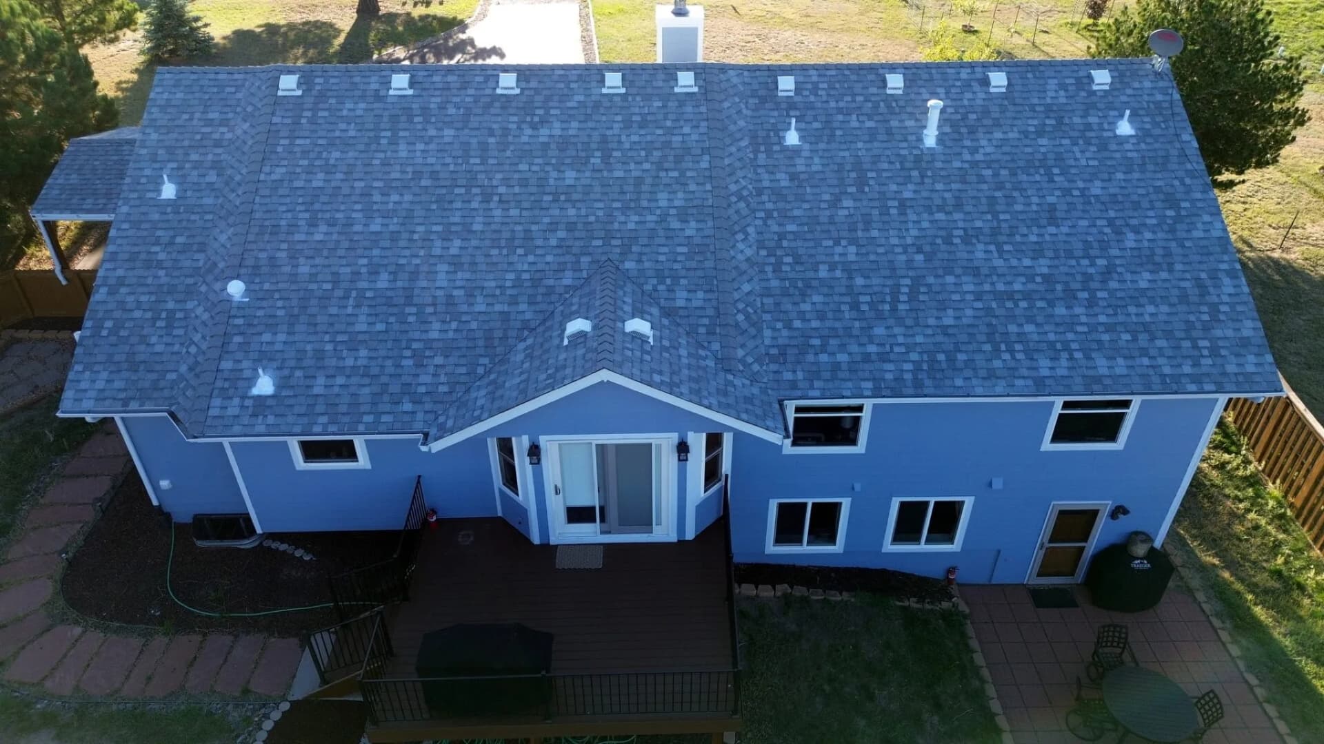 Aerial view of a completed architectural asphalt shingle roof on a two-story home on a wooded acreage lot in Elizabeth, Colorado
