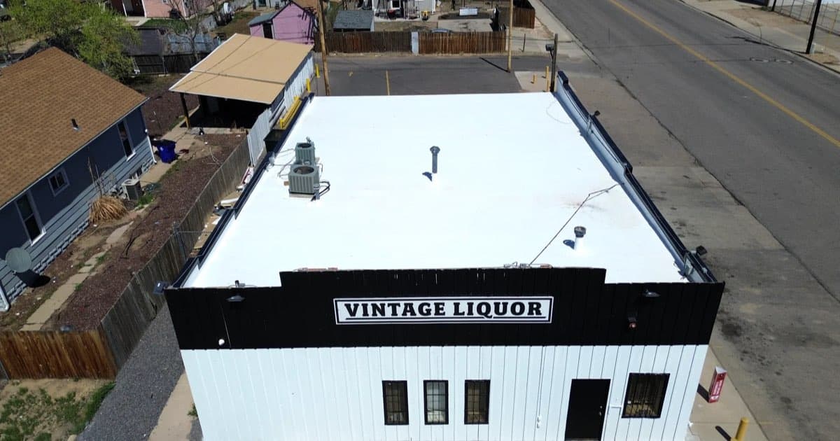 A completed white TPO membrane roof on a commercial building in Greeley, Colorado, with heat-welded seams running the length of the roof field and rooftop units curbed and flashed
